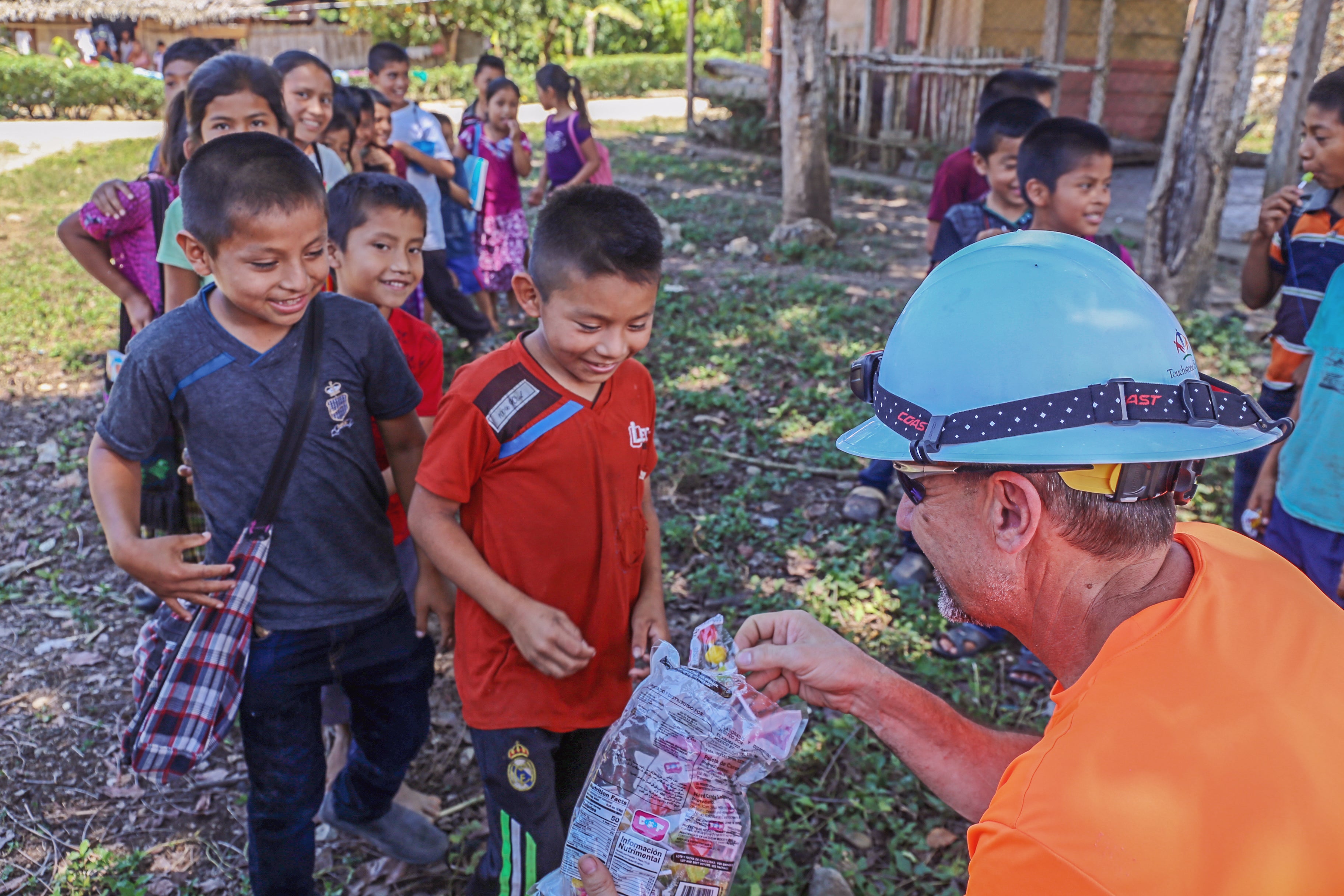 A man in a hard hat with a group of children