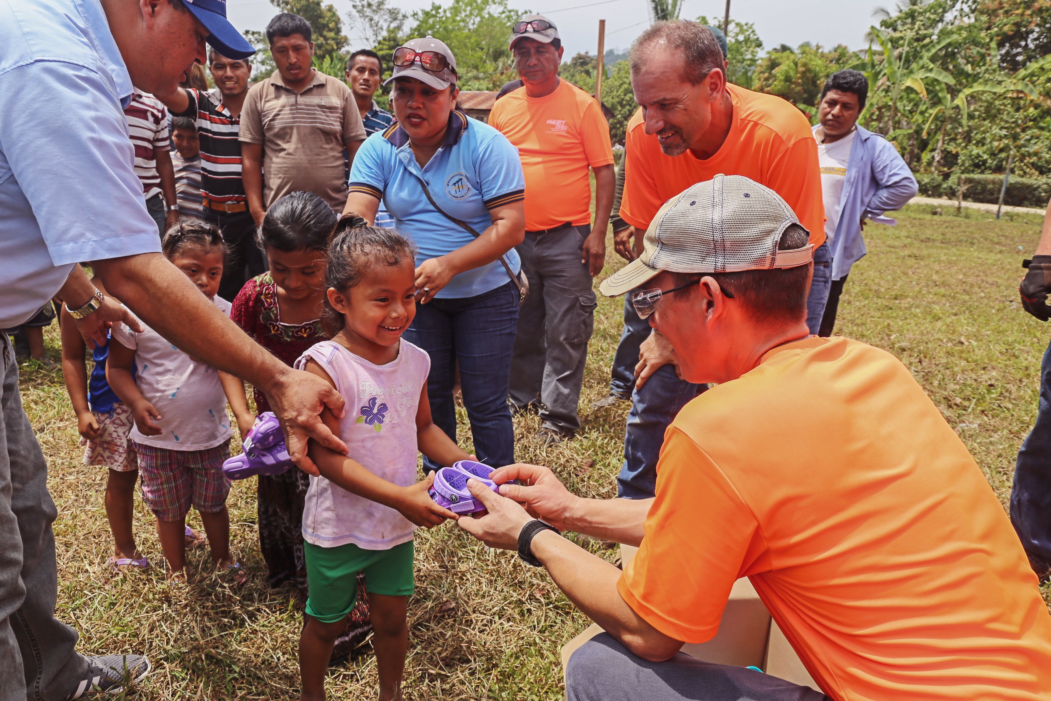 A man handing out items to a group of children
